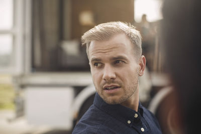 Young businessman looking away with portable office truck in background