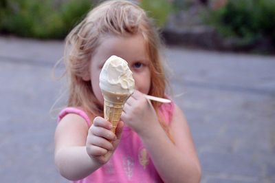 Portrait of girl having ice cream cone while standing on field