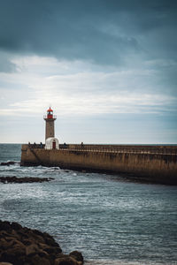 Lighthouse by sea against sky
