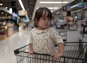 Cute girl in shopping cart at supermarket