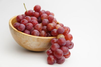 Close-up of grapes in bowl against white background