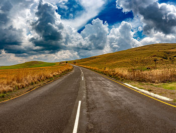 Road amidst field against sky