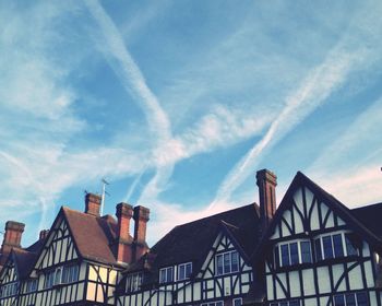 Low angle view of houses with smoke stacks against sky