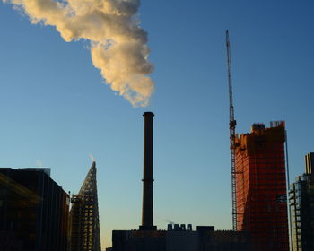 Low angle view of smoke emitting from factory against sky