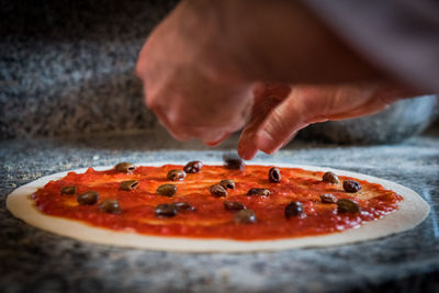 Cropped image of hands making pizza on table