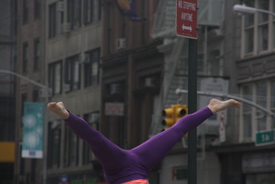 Low section of woman doing split handstand against buildings