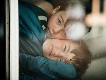 Portrait of brothers embracing seen through window
