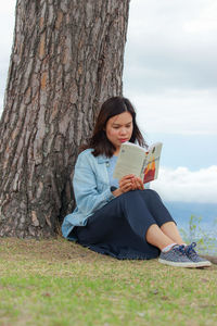 Young woman sitting on tree trunk