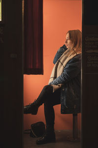 Reflection of woman sitting on chair in mirror at home