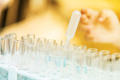 Cropped hand of person examining test tubes in rack at medical laboratory