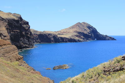 Scenic view of sea and mountains against clear blue sky