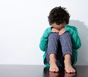 Boy sitting on floor against white background stock photo