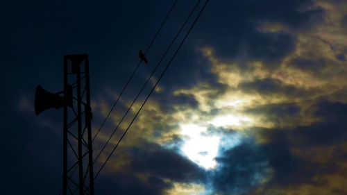 Low angle view of electricity pylon against cloudy sky