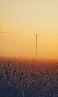 Electricity pylon on field against sky during sunset