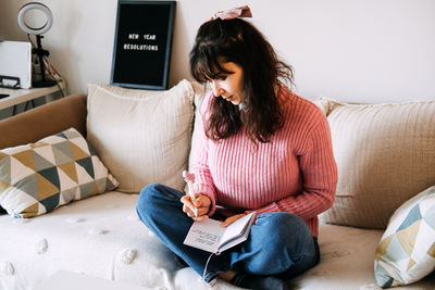 Young woman using digital tablet while sitting on sofa at home