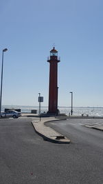 Lighthouse by sea against clear sky