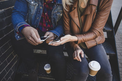 Midsection of couple using mobile phones on steps