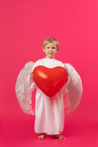Portrait of smiling girl standing against red background
