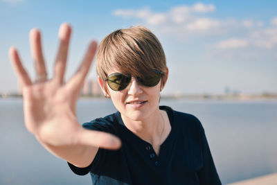  portrait of mid adult woman wearing sunglasses showing stop sign