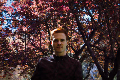 Portrait of young man standing against trees