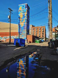 Road by buildings against blue sky