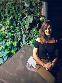 Portrait of smiling young woman against plants