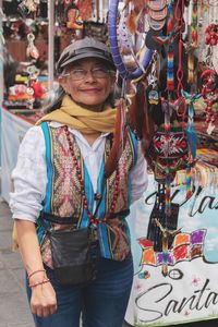 Full length portrait of smiling young woman standing in market