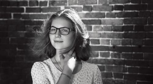 Portrait of teenage girl in eyeglasses against brick wall