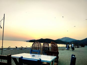 People by sea against clear sky during sunset