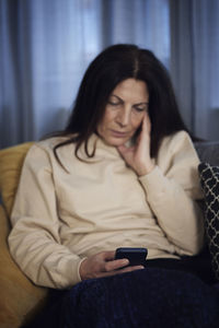 Woman on sofa using cell phone