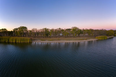 Scenic view of lake against clear sky at sunset