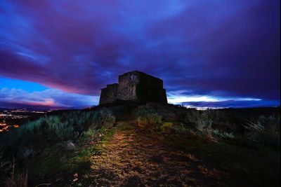 Built structure on landscape against cloudy sky
