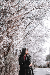 Full length of woman standing by sakura tree in winter