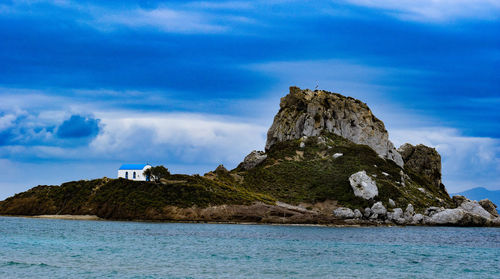 Rock formations by sea against blue sky