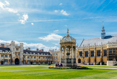 Low angle view of trinity college against cloudy sky during sunny day