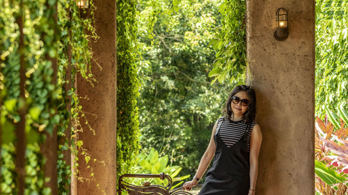 Portrait of smiling young woman standing against trees