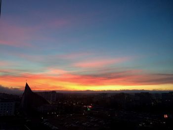 Cityscape against dramatic sky during sunset