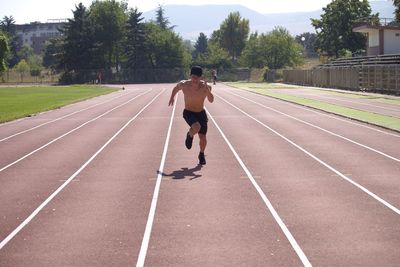 Shirtless man running on track