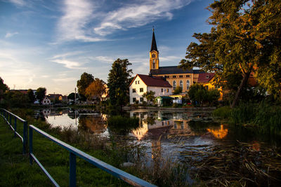 Water amidst buildings and trees against sky