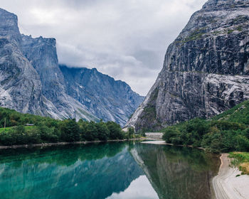 Detailed layered mountain cliffs and trees over a river