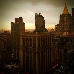 Buildings in city against cloudy sky