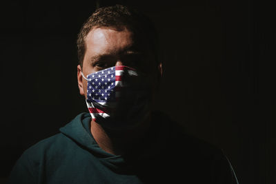 Close-up portrait of man wearing mask against black background