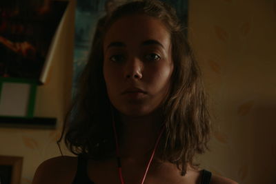 Close-up portrait of young woman listening to music through in-ear headphones