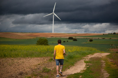 Rear view of man on field against sky