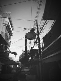 Low angle view of electricity pylon against sky in city