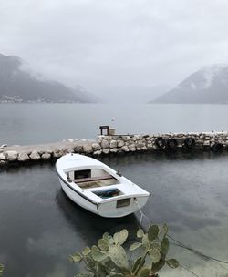 Boat moored on lake against sky