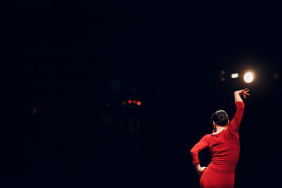 Rear view of woman dancing at night