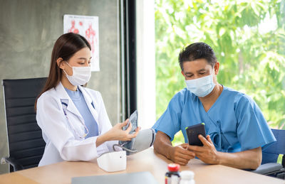 Doctor and patient wearing mask having discussion