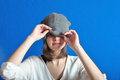 Portrait of woman wearing hat against blue background