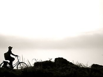 Silhouette of man with bicycle against sky